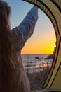 woman with long hair in a tent meets the sunrise on the sea coast, rear view. Travel and tourism Royalty Free Stock Photo