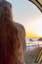 woman with long hair in a tent meets the sunrise on the sea coast, rear view. Travel and tourism Royalty Free Stock Photo