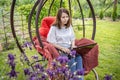 Woman with long hair typing at a laptop while sitting in a nest chair