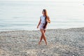 Beautiful woman with long hair walks on the beach by the sea Royalty Free Stock Photo