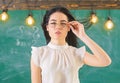Woman with long hair in white blouse stands in classroom. Lady strict teacher on calm face stands in front of chalkboard Royalty Free Stock Photo