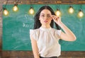 Woman with long hair in white blouse stands in classroom. Strict teacher concept. Lady strict teacher on calm face Royalty Free Stock Photo