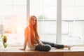 Woman with long hear sitting at home next to the window at morning sunrise light looking at camera with ch Royalty Free Stock Photo