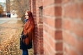 Woman with long red hair walks in autumn on the street. Mysterious dreamy look and the image of the girl. Redhead woman walking Royalty Free Stock Photo