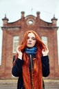 Woman with long red hair walks in autumn on the street. Mysterious dreamy look and the image of the girl. Redhead woman walking Royalty Free Stock Photo