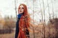 Woman with long red hair walks in autumn on the street. Mysterious dreamy look and the image of the girl. Redhead woman walking Royalty Free Stock Photo