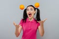 Woman with long straight hair, holding two oranges, looking up