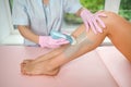 Woman with long tanned perfect legs and smooth skin having wax stripe depilation hair removal procedure on legs in beauty salon. Royalty Free Stock Photo