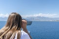Woman look at the sea, at the beautiful bay and islands through binoculars, rear view. travel and tourism Royalty Free Stock Photo
