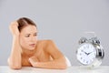 Woman looking at an alarm clock in consternation