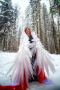 Woman looking as fairy angel with wings with white feathers in the forest with snow and snowdrifts on cold winter day Royalty Free Stock Photo