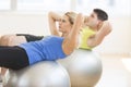 Woman Looking Away While Exercising On Fitness Ball At Gym