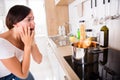 Woman Looking At Burnt Food In Cooking Pot