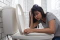 Woman looking at camera drunk hangover puke in toilet bowl. Female have abdominal pain, nausea, dizziness, nausea, vomit due to Royalty Free Stock Photo