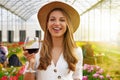 Woman looking at camera and holding glass of wine with people among flowers field drinking and chatting on the background Royalty Free Stock Photo