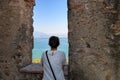 Woman looking through a castle window at Lake Garda