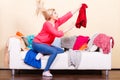 Woman looking through clothes on messy couch Royalty Free Stock Photo