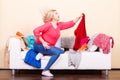 Woman looking through clothes on messy couch Royalty Free Stock Photo