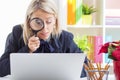 Woman looking at computer screen through a magnifying glass Royalty Free Stock Photo