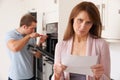 Woman Looking Concerned At Domestic Repair Bill Royalty Free Stock Photo