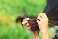 Woman looking at damaged splitting ends of hair on nature background, Haircare concept