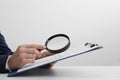 Woman looking at document through magnifier at white table, closeup. Searching concept