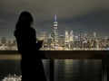 woman looking at downtown manhattan nyc skyline (after sunset, night time) world trade center cityscape