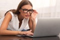 Woman Looking Through Eyeglasses At Laptop Sitting On Couch Indoor Royalty Free Stock Photo