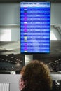 Woman in international airport looking at the flight information board checking her flight. Travel and transport concept Royalty Free Stock Photo