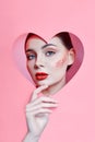 Woman looking in the heart hole, bright beautiful makeup, big eyes and lips, bright lipstick, professional cosmetics and facial