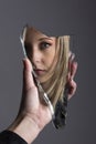 Woman looking at her face in shard of broken mirror Royalty Free Stock Photo