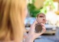 Woman looking in her pocket mirror selective focus defocused background. Check if everything is right. Beauty treatment