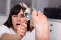 Woman Looking At Her Toe Nails With Magnifying Glass Royalty Free Stock Photo