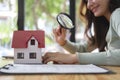 Woman looking at the house model with a magnifying glass. Real estate appraisal, land valuation and house selection concept Royalty Free Stock Photo