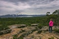 A woman looking at incoming storm on sandstone cliff of Reeds Lookout in Grampians National Park, Victoria, Australia.