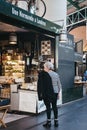 Woman looking inside French charcuterie and cheese stand in Borough Market, London, UK.