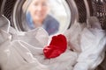 Woman Looking Inside Washing Machine With Red Sock Mixed With White Laundry