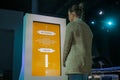 Woman looking at interactive display of vertical electronic kiosk