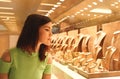 Woman looking at jewelry in store window. Girl chooses silver, gold, diamonds, precious stones