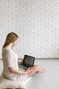 Woman looking on laptop near black white wall