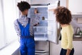 Repairman Checking Refrigerator With Digital Multimeter