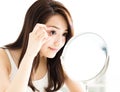 Woman looking into mirror and checking eyes