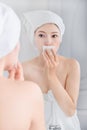 Woman looking mirror and cleaning her face with cotton Royalty Free Stock Photo