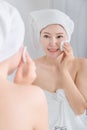 Woman looking mirror and cleaning her face with cotton Royalty Free Stock Photo