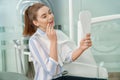 Woman looking at mirror and enjoying smile in dental office Royalty Free Stock Photo