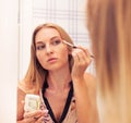 Woman looking in the mirror and putting make up on Royalty Free Stock Photo