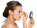 Woman looking into mirrorand using tweezers