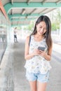 Woman looking at mobile phone and walking in light rail station Royalty Free Stock Photo