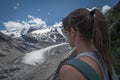 Woman looking at Morteratsch Glacier in the Engadin in the Swiss Alps in summer with blue sky and sun