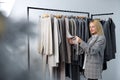 Woman looking at new collection of stylish clothes on hangers clothing rack rails